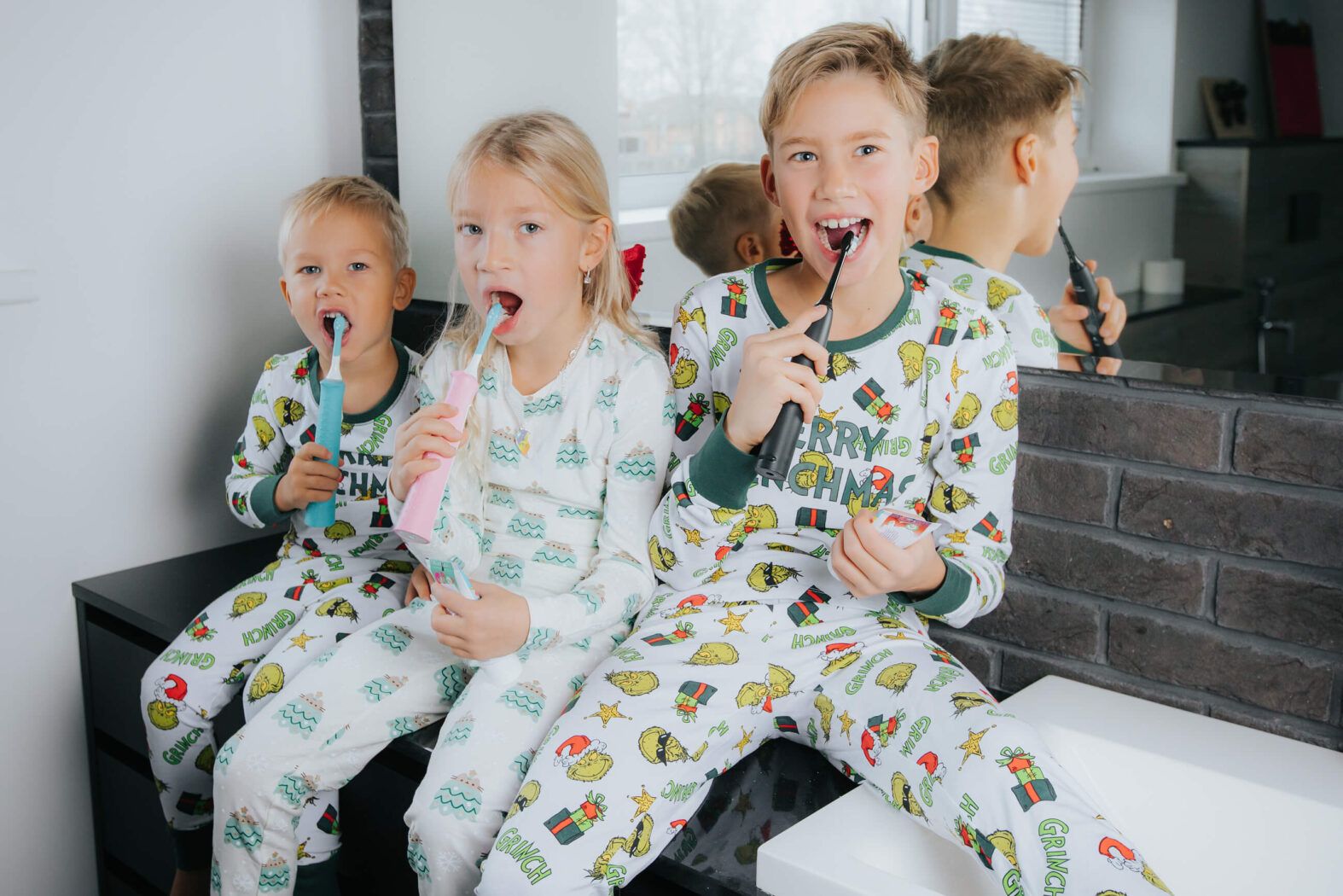 Trīs priecīgi bērni tīra zobus